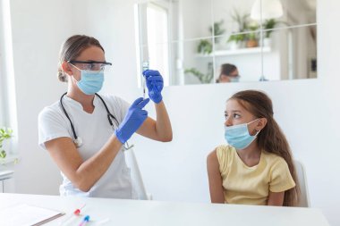 Virüse karşı bağışıklık kampanyası konsepti. Doktor aşılayan kız. Tıbbi maskeli kız covid-19 aşısı oluyor, doktor hastanede koronavirüs aşısı yapıyor..
