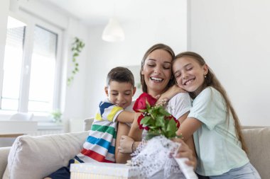 Hediye kutusu olan neşeli küçük bir kız ve gül buketi olan en küçük erkek kardeşi gülümseyerek anneler gününü evde kutluyor. Anneler Günün kutlu olsun.!