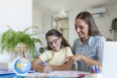 Annesiyle evde ödev yapan tatlı bir kız. Bir anne küçük kızının okul için ev ödevini yapmasına yardım eder. Eğitim ve aile kavramı