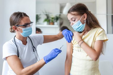 Doktor aşılayan kız. Hastanın koluna COVID-19 aşısı enjekte ediyorum. Tıbbi maskeli kız covid-19 aşısı oluyor, doktor hastanede koronavirüs aşısı yapıyor..