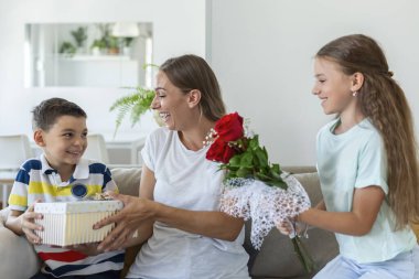Bir buket gül çiçeğiyle neşeli küçük bir kız ve hediye kutusuyla gülümseyen ve anneler gününde annelerini tebrik eden en küçük kardeşi. Anneler Günün kutlu olsun.!