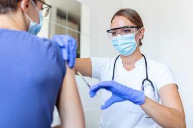 Pratisyen hekimin klinikteki eski hastaya fotokopi alanı aşılaması. Doktor, hastanedeki yaşlı adama iğne yapıyor. Covid-19 ya da koronavirüs aşısı yapmadan önce elinde şırınga tutan hemşire. HPV aşısı