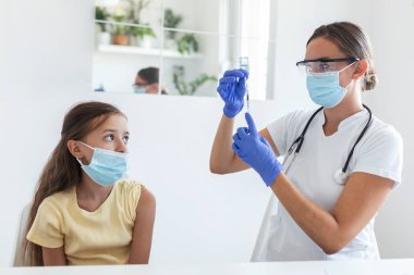 Virüse karşı bağışıklık kampanyası konsepti. Doktor aşılayan kız. Tıbbi maskeli kız covid-19 aşısı oluyor, doktor hastanede koronavirüs aşısı yapıyor..