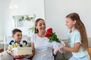 Bir buket gül çiçeğiyle neşeli küçük bir kız ve hediye kutusuyla gülümseyen ve anneler gününde annelerini tebrik eden en küçük kardeşi. Anneler Günün kutlu olsun.!