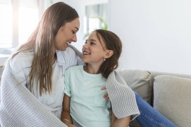 Hoş bir kız ve annesi güneşli bir sabahın tadını çıkarırlar. Evde iyi eğlenceler. Çocuk uykudan uyanıyor. Aile yatak odasındaki yatakta battaniyenin altında oynuyor..