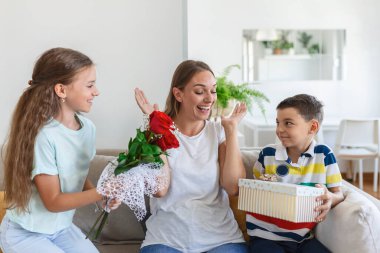 Bir buket gül çiçeğiyle neşeli küçük bir kız ve hediye kutusuyla gülümseyen ve anneler gününde annelerini tebrik eden en küçük kardeşi. Anneler Günün kutlu olsun.!