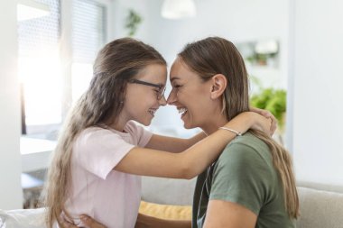 Tatlı güzel kızının genç annesine sarılıp yattığı yakın çekim. Sevgili anne, tatlı kızını evdeki kanepede kucaklıyor..