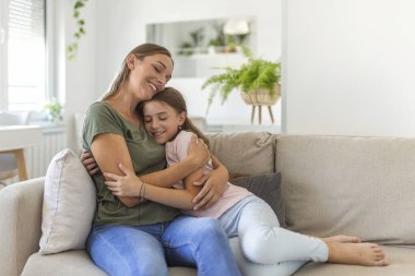 Seni o kadar çok seviyorum ki. Mutlu genç anne portresi oturma odasında gülümseyen tatlı küçük kız, sevgi dolu okul çağındaki kız milenyum bayan dadıyı ya da koruyucu anneyi kucaklıyor.