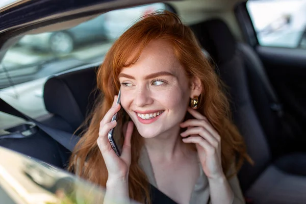 Young girl uses a mobile phone in the car. Technology cell phone isolation. Internet and social media. Woman with smartphone in her car. Girl is using a smartphone in car