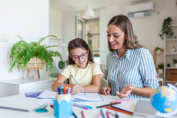 Caucasian woman looking proud at her daughter during homeschooling and doing some painting.