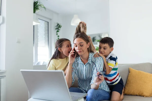 Upset mother having problem with noisy naughty daughter and son jumping on couch and screaming, demanding attention, frustrated mum tired of difficult child trying to work from home