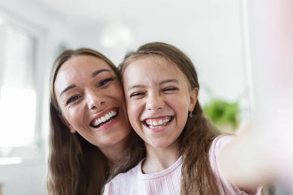 Little daughter young mother faces webcam close up view. Adorable kid girl use smartphone have fun with older sister making selfie photography, vloggers record new vlog, enjoy funny activity concept