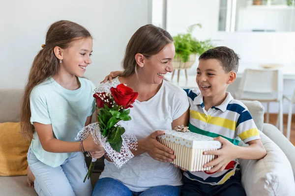 Hediye kutusu olan neşeli küçük bir kız ve gül buketi olan en küçük erkek kardeşi gülümseyerek anneler gününü evde kutluyor. Anneler Günün kutlu olsun.!