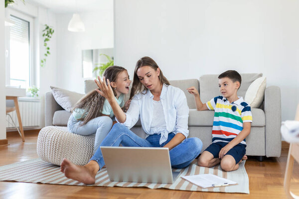 Little naughty children distracting busy young woman from work on laptop at home