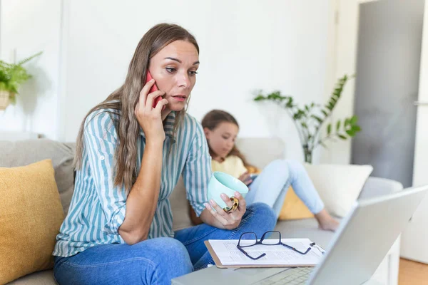 A working mother multitasking. Single mother with a kid trying to work. Worried woman working at home while her daughter is not letting her. Quarantine isolation during the Covid-19 health crisis