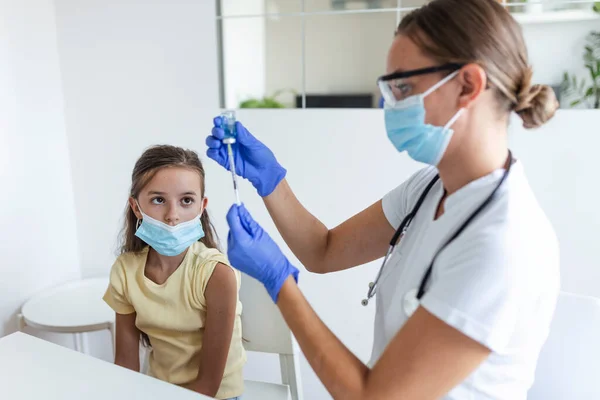 Antiviral immunization campaign concept.Doctor vaccinating girl. Girl in medical masks getting vaccinated against covid-19, doctor giving injection of coronavirus vaccine at hospital.