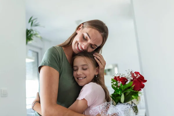 I love my you mom! Attractive young woman with little cute girl are spending time together at home, thanking for handmade card with love symbol and flowers. Happy family concept. Mother\'s day.