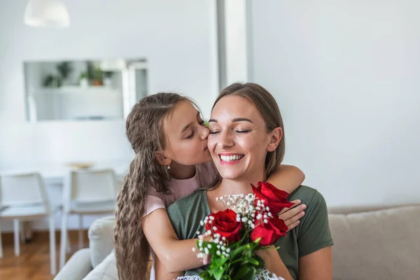 I love my you mom! Attractive young woman with little cute girl are spending time together at home, thanking for handmade card with love symbol and flowers. Happy family concept. Mother\'s day.