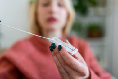 Kadın evde koronavirüs PCR testi yaparken pamuk çubuğu kullanıyor. Coronavirus hızlı tanı testi uygulayan bir kadın. Evde genç bir kadın COVID-19 için burun çubuğu kullanıyor..