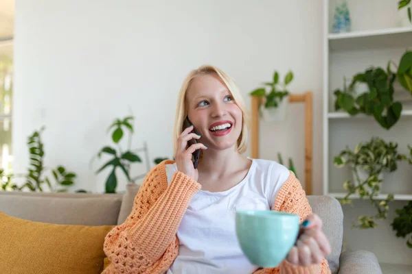 Mulher Sorrindo Atraente Usando Telefone Inteligente Enquanto Sentado Sofá Casa — Fotografia de Stock