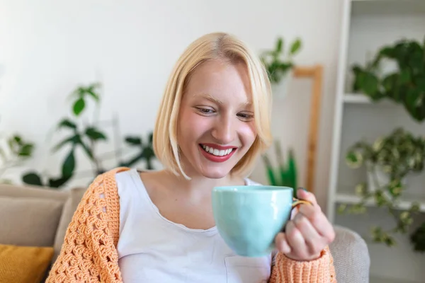 Closeup view of young woman with cup of hot drink at home, blank space. People, drinks and leisure concept - happy young woman with cup of tea or coffee at home