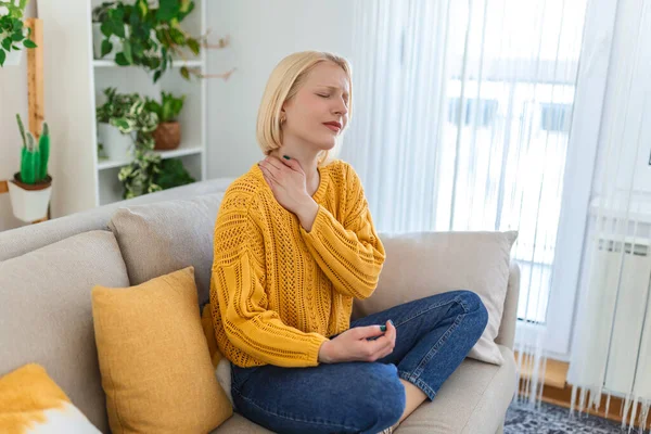 Pain in the shoulder. Upper arm pain, People with body-muscles problem, Healthcare And Medicine concept. Attractive woman sitting on the bed and holding painful shoulder with another hand.