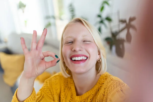  Mischievous young woman takes selfie at home. Beautiful blond woman ok ...