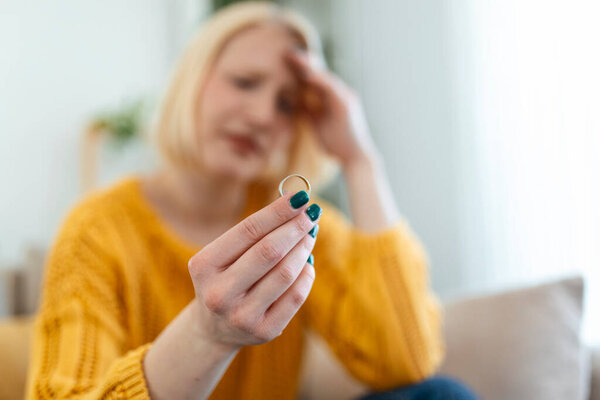 Young woman holding wedding engagement ring in hands, engaged girl doubts about marriage proposal, abandoned wife depressed after getting divorced, help to overcome breaking up, starting new life