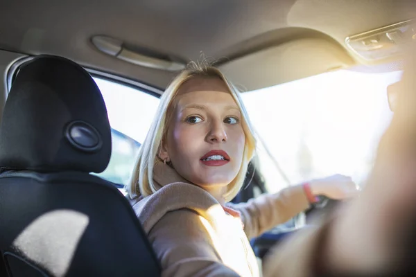 車の中で女性の屋内後部座席のアイデアタクシーの運転手の乗客を見て回る 試験車両の概念 魅力的な若い女性のバックビュー彼女の肩の上に見ながら車を運転 — ストック写真