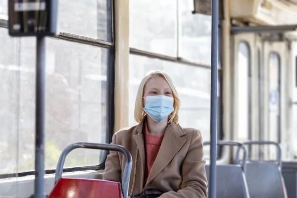 Woman With Protective Face Mask In Bus Transport. Young woman wearing protective face mask, she sitting in bus transportation in the city.. Woman with mask in bus