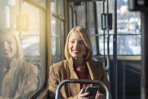 people in public transport, commuters, woman passenger looking at the screen of her smartphone