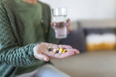 Hasta ve hasta, olgun bir kadının elinde farklı haplar tutarak kamerada tıbbi hazırlıkları göstermesi.