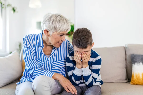 Loving understanding old grandma embracing little crying boy comforting upset grandson, senior caring grandmother hugging child consoling kid in tears, grannys empathy support for grandchild