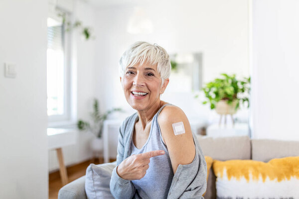 Женщина указывает на свою руку бинтом после получения вакцины от ковида-19. Зрелая женщина показала плечо после вакцины от коронавируса