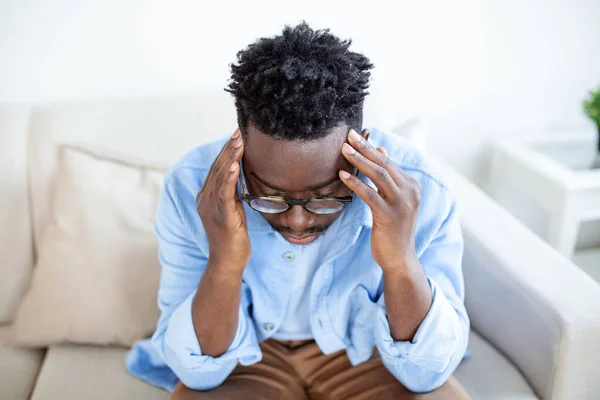 Tired African American man taking off glasses, exhausted massaging nose bridge, suffering from eye strain after long computer work, feeling pain, health problem concept