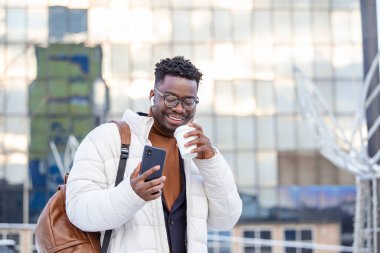 Elinde kahve tutan genç bir işadamının sokak portresi.