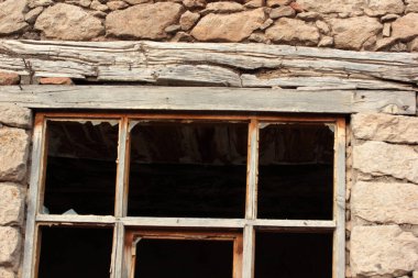 Terk edilmiş bir taş evin kırık penceresi.