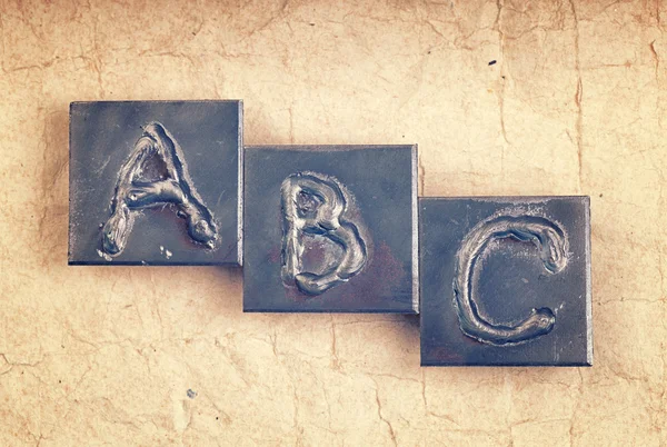 Die Phase "abc" aus Metallbuchstaben auf altem Altpapier — Stockfoto