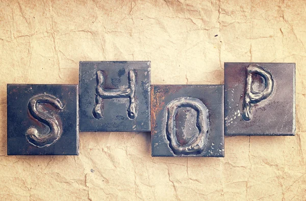 La parola "SHOP" fatta da lettere metalliche su una vecchia carta vintage — Foto Stock