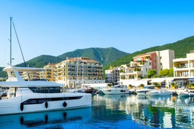 Tivat, Karadağ - 18 Haziran 2022: Porto Karadağ 'daki yat marinasının deniz kenarındaki konutları ve güzel gezinti alanlarıyla gün batımı manzarası