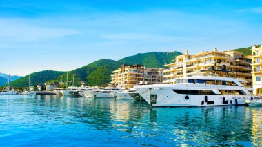 Tivat, Karadağ - 18 Haziran 2022: Porto Karadağ 'daki yat marinasının panoramik günbatımı manzarası, liman evleri ve güzel gezinti güvertesi