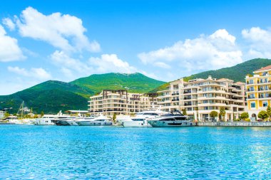 Tivat, Karadağ - 18 Haziran 2022: Porto Karadağ 'daki yat marinasının deniz kenarındaki konutları ve güzel gezinti alanlarıyla gün batımı manzarası