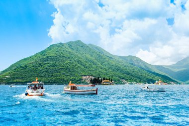 Perast, Montenegro - May 28, 2022: Beautiful summer landscape of the Bay of Kotor coastline - Boka Bay with excursion boats near the landmarks 