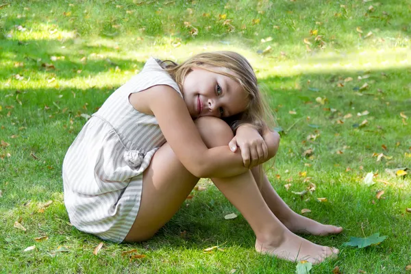 Cute girl sitting on green grass — Stock Photo, Image