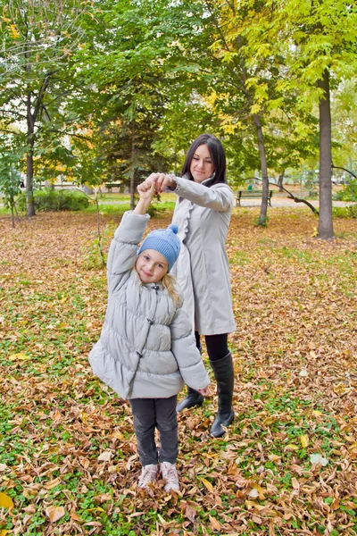 Smiling mother and daughter play in autumn — Stock Photo, Image