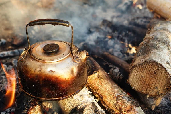 Sooty teapot on camping bonfire — Stock Photo, Image