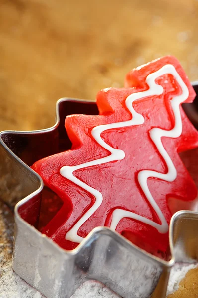 Árvore de natal doces vermelhos em cortador de biscoitos, fundo de madeira — Fotografia de Stock