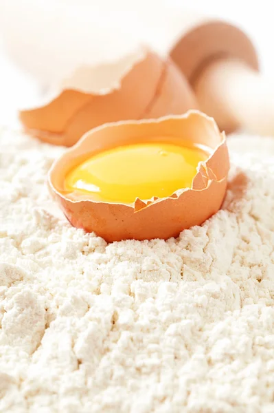 Huevo roto con cáscaras sobre harina, fondo blanco —  Fotos de Stock