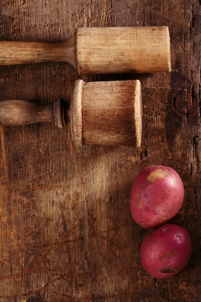 アンティークのジャガイモつぶし器、赤と古い木製テーブル上にナイフ — ストック写真