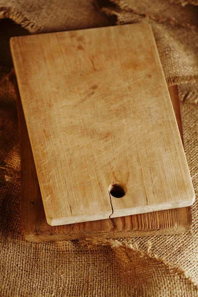 Velho woden choppig board em fundo hessiano, raso dof — Fotografia de Stock